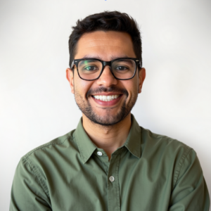 Persona con cabello corto y oscuro, usando camisa verde oliva abotonada, frente a un fondo blanco liso.