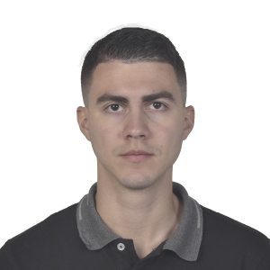 Persona de pie vistiendo una camiseta tipo polo negra con cuello gris, frente a un fondo blanco.