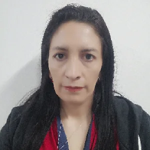 Persona de pie frente a un fondo claro, vistiendo una prenda roja bajo una chaqueta oscura.
