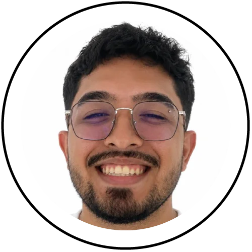 Persona en fotografía tipo retrato, centrada dentro de un marco circular, vistiendo gafas de montura metálica, con barba corta y fondo claro uniforme.