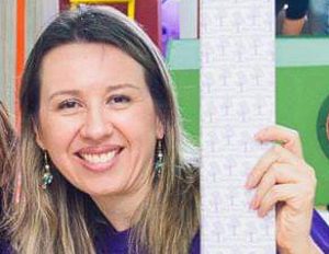 Persona sostiene una hoja rectangular con múltiples ilustraciones pequeñas impresas, en un entorno interior colorido.