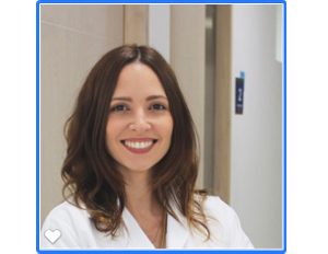 Persona con bata blanca está en un entorno interior, con paredes claras y una puerta visible al fondo.