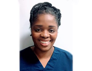 Persona con uniforme azul tipo bata médica, frente a un fondo blanco.