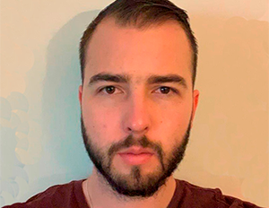 Persona de cabello corto y oscuro, vestida con camiseta color vino, está frente a una pared clara.